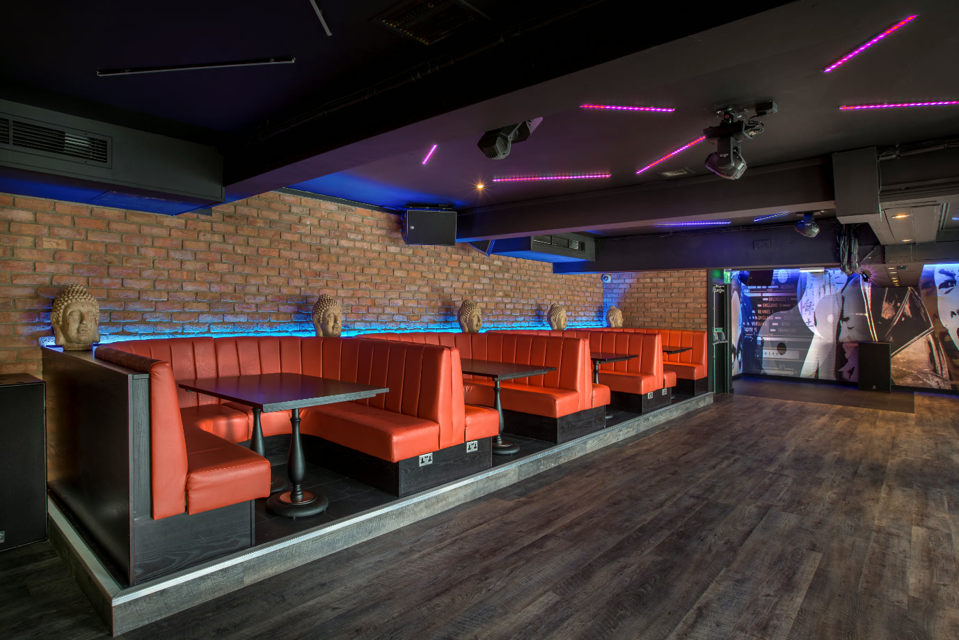 Late-night party floor at Rendezvous Weymouth — exposed brick, neon booth seating and DJ space